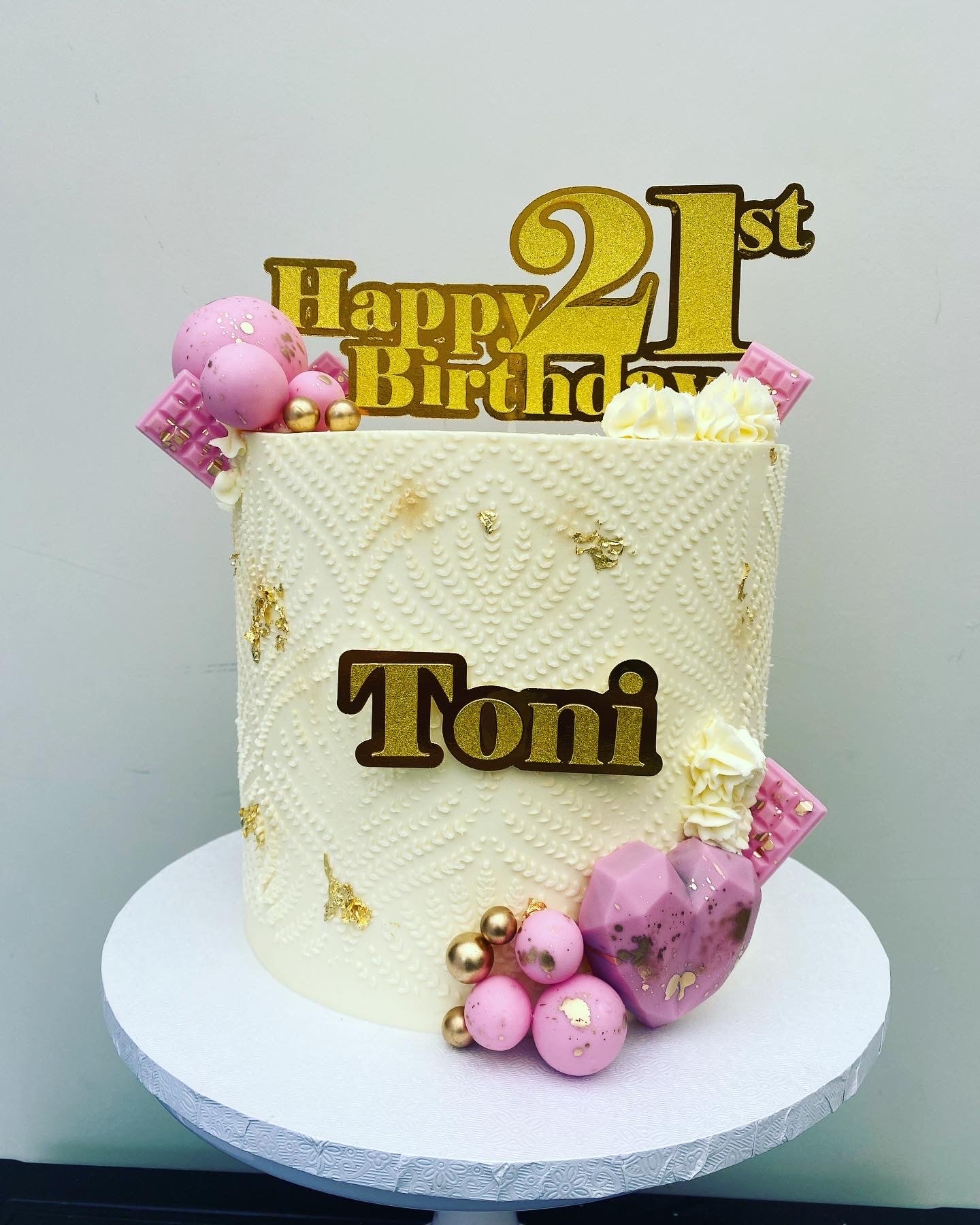 Cream buttercream cake with gold and pink decorations